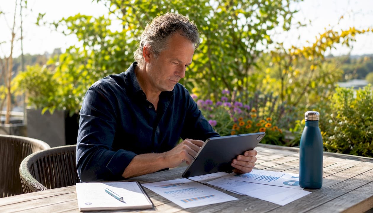 Thuis aan de keukentafel houdt een man zich bezig met energiehandel via zijn tablet.