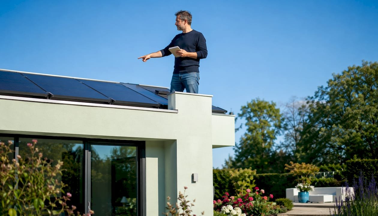 Een huiseigenaar bekijkt de zonnepanelen op zijn dak om te controleren of alles nog goed werkt.